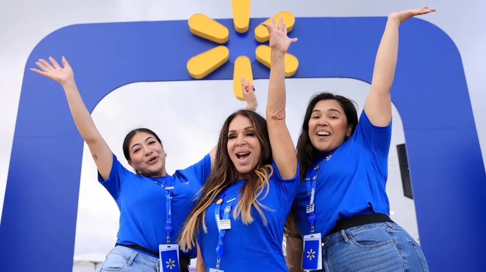 Three store associates cheering with their arms raised outside a shop
