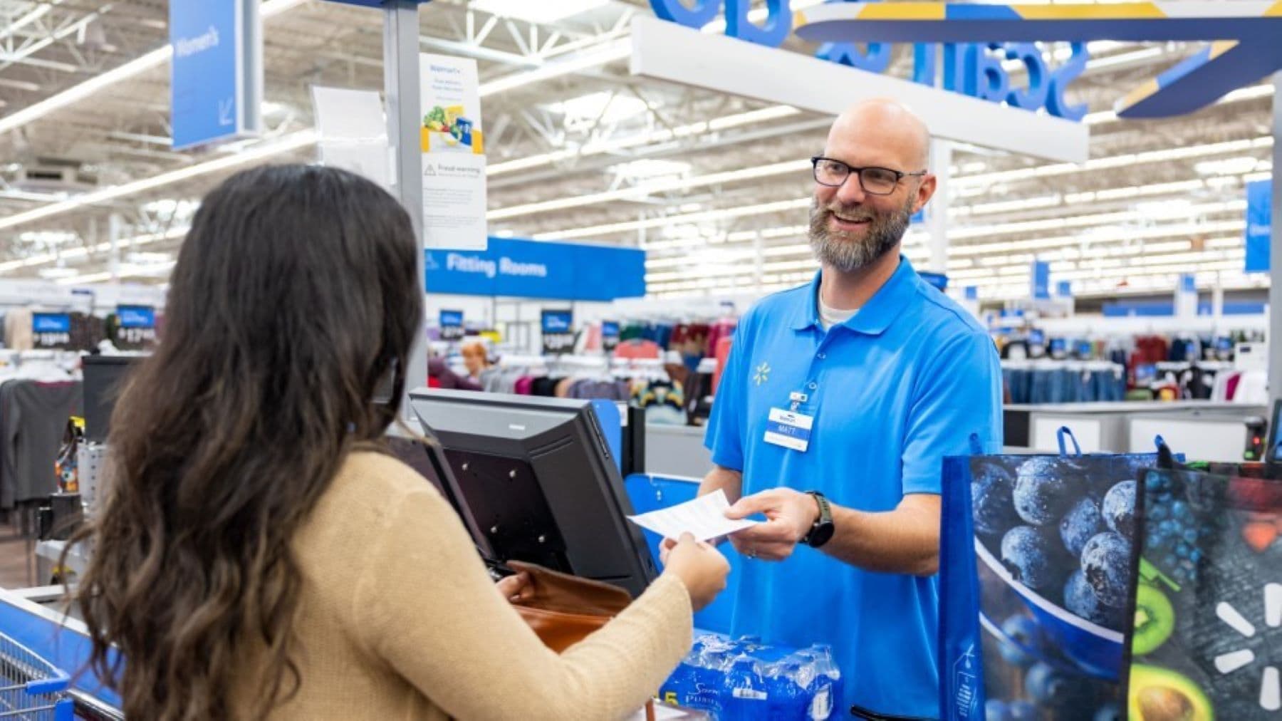 A store associate handing a receipt to a shopper at a checkout counter